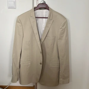 Tiger of Sweden Kavaj - Herr - Beige Tiger of Sweden kavaj i nyskick.  Aldrig använd, säljs med etiketter. Strl 56.  Inköpt för 2399 kr, ordinarie: 3999 kr. 