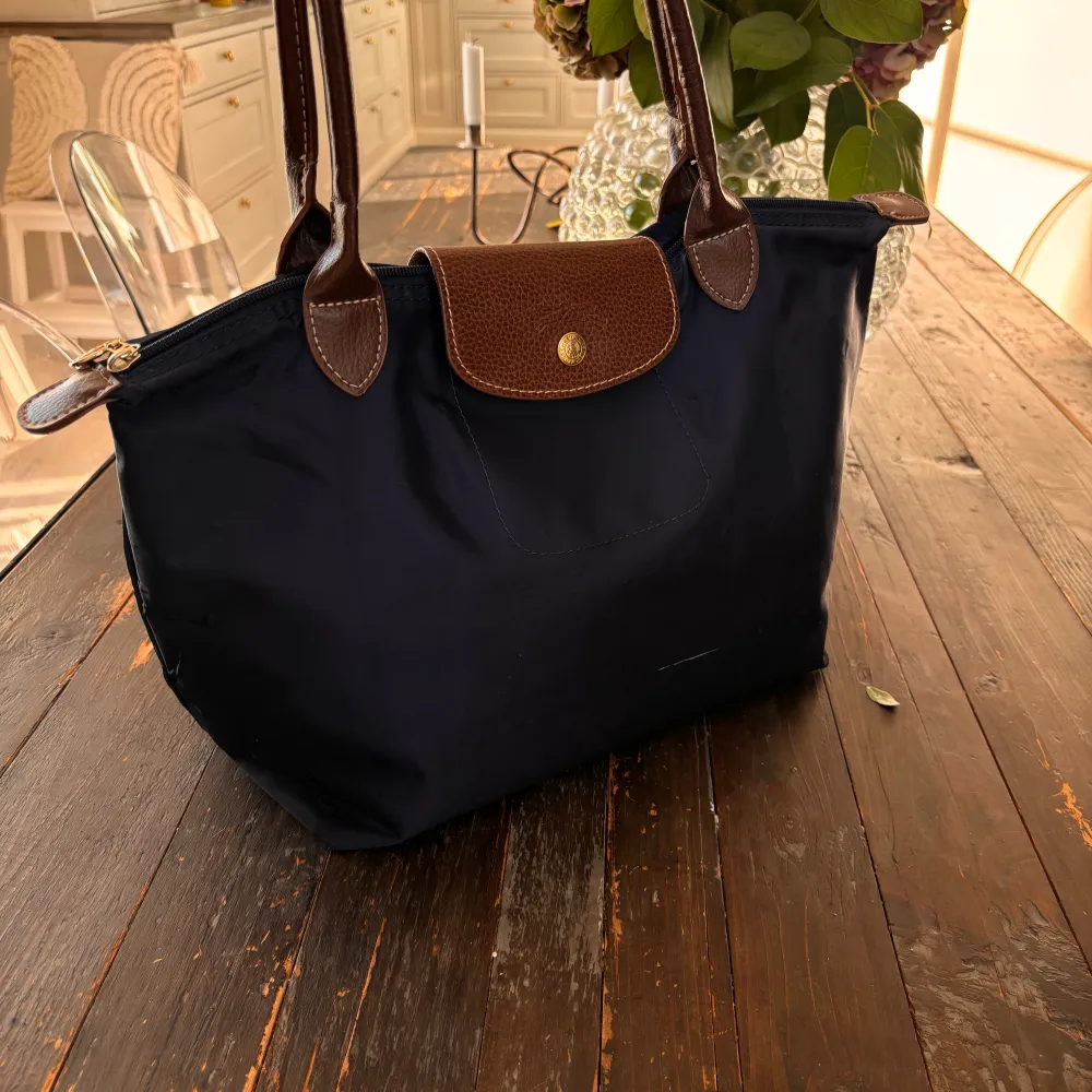Longchamp väska i färgen marin blå, storlek medium. Väskan har några få defekter som syns på bild, (fram och baksida). Mått: 28 cm (L) x 26,5 cm (H) x 15,5 cm (W). Nypris 1350kr. Skriv för fler bilder vid intresse.🙏🏼. Väskor.