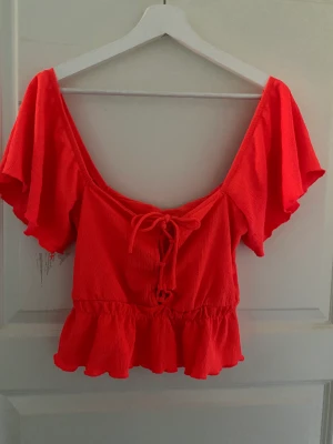 Coral röd sommartopp  - Säljer min helt oanvända topp. Jättefin på sommaren. Helt ny med prislappen på fortfarande. Är i storlek Xs men passar även S. Säljer för 100 då den kostar 279 nypris