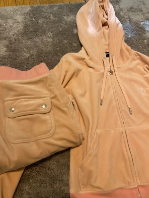 Rosa juicy set💘 - Juicy couture set i färgen pale pink! På mina bilder ser färgen mer beige ut men på den 3e bilden syns den riktiga! Byxorna är stolek XS men skulle säga att de passar S. Tröjan är S men liten i storleken så passar även XS/XXS. Snöret på byxorna saknas💞