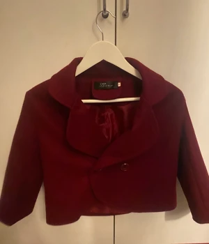 En vinröd trekvarts kappa - Den är liten i storlek, jag brukar ha M i jackor.