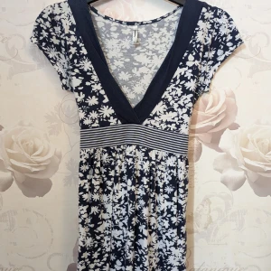 Blus t-shirt - En t-shirt som är tajtare upptill och lös under bysten med ett band man kan knyta antigen i back eller i fram. Något urtvättad men inga hål.