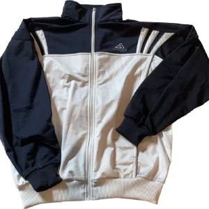 Adidas kofta - Lite retro adidas tröja. Lite tunnare i tyget, perfekt på sommarn eller vid träning. Mycket bra skick, inte använd så mycket, köpt på humana. Skitsnygga armar som är lite oversized! Marinblå och silvergrå 