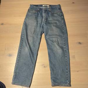 Baggy levis jeans me fåtal skador, tex vid knäet och lite nere vid ankeln. 