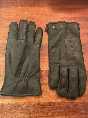 J Lindeberg Läderhandskar M -  Säljer ett par väldigt fina läderhandskar då de är lite stora för mig. De är i nyskick, finns inga tecken på användning. Det är lamm nappa läder av högsta kvalitet. Fodret är en 70, 30 blandning av ull och kashmir. Nypris 800kr. 