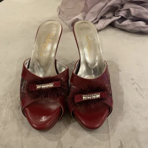 Röda klackar - Ett par jättesöta vinröda klackskor med spets, strass och fluff på, i storlek 37. Säljer då de är för små.  Det är en jätte jätteliten svart fläck på den högra skon, man ser den på bild 1. Skriv privat för mer info och bilder. 