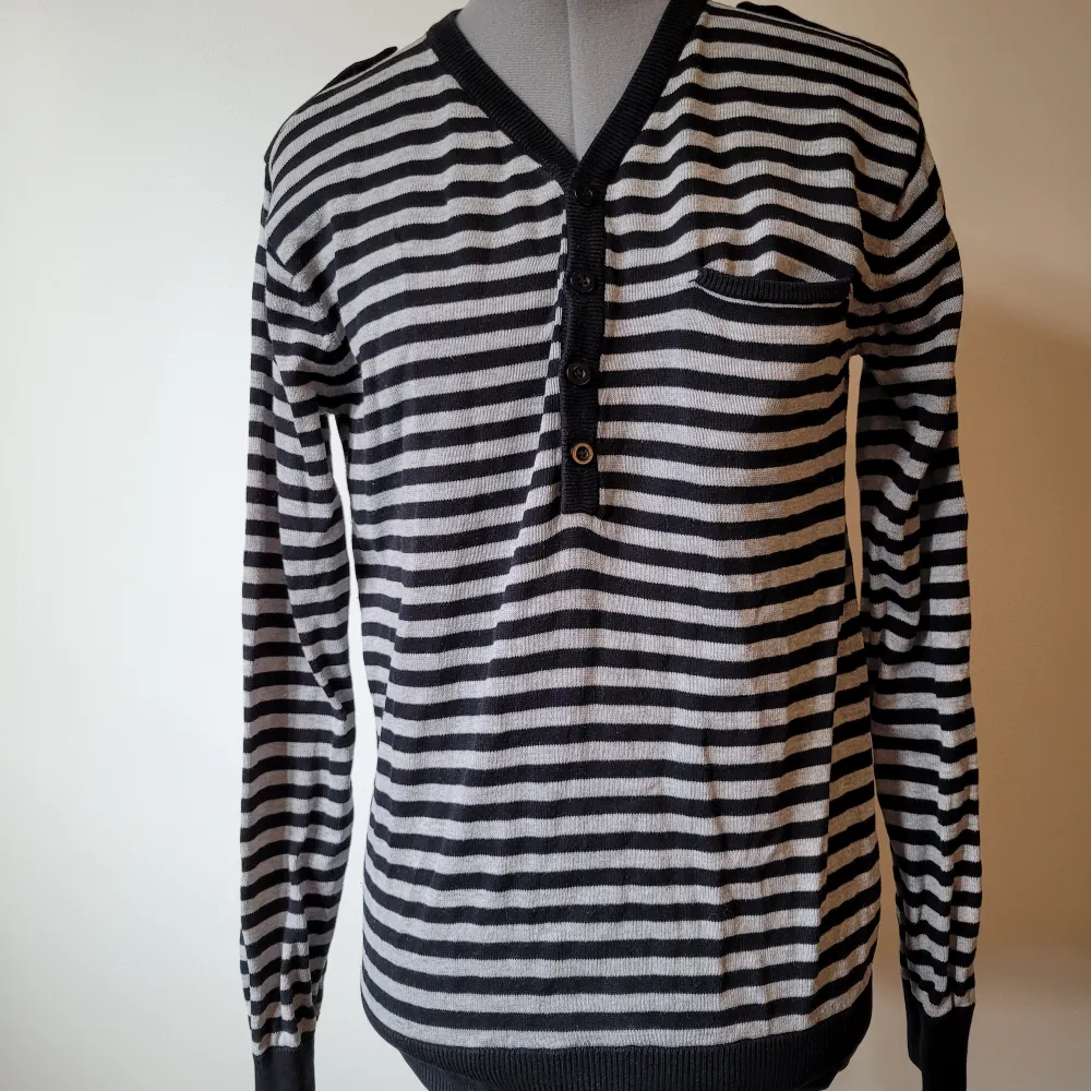 Randig v-ringad grå och svart långärmad tröja med en bröstficka, knappar och detaljer på axlarna.. Tröjor & Koftor.