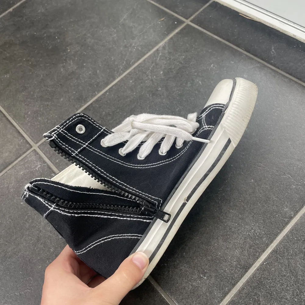 Fake Converse sneakers som är svarta med dragkedja på insidan och snörning upptill. Bra skick och liknas höga Converse mycket, särskilt när man har byxor och bara toppen syns. . Skor.