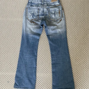 Jeans med nitar  - Byxorna är lågmidjade och Flare/utsvängda. Nitar både vid fram och bak fickan. I fram sitter alla bitarna kvar men i bak saknas några men det är inget som syns (det finns inga hål) och inget som märks, se bild. Använd gärna köp nu💕 
