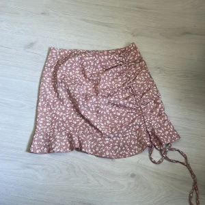 blommig kjol - en rosa blommig kjol som man knäpper i sidan 