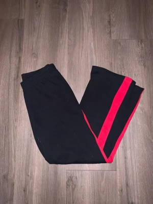 Svarta byxor  - Svarta byxor med en röd sträng på sidan midjan och neråt använd 1-2 gånger! 