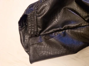 Skinkjol  - En skinkjol i imitation från lindex. Aldrig använt resåren i midjan och dragkedja i sidan. Slits baktill. Glansig med krokodil mönster. Midjehög modell 