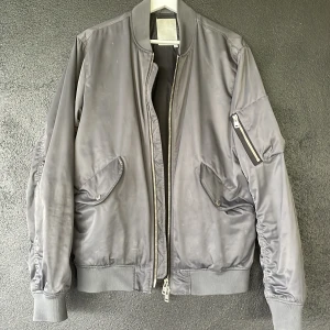 Bomberjacka J.Lindegerg - Säljer en grymt snygg vår/höstjacka från J.Lindeberg. Jackan väl använd och finns därmed tecken på lite slitage. Färgen är av silvergrå karaktär, passar sjukt bra till ett par svarta jeans och en vit/svart t-shirt. 