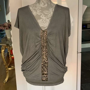 Festlig tunika - Festlig Tunika i färgen grå. Har bara använt den en gång till Melodifestivalen. I storlek S. Men den är oversize. Den har guldiga paljetter i mitten. För 100kr. 