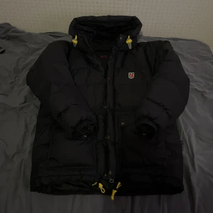 Fjällräven Jacka - Fjällräven jacka i använt men fint skick. Några pyttesmå hål där dun försöker tränga igenom, men ingen reva eller större hål.
