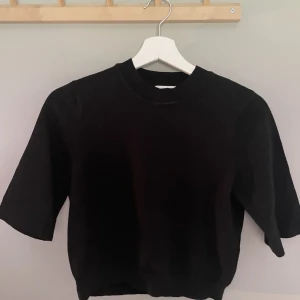 Svart kortärmad tröja  - Stickad svart tröja i medium men mer som en small. Kort med trekvartslånga ärmar. 