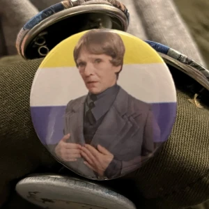 Uni sax pin med ickebinär flaggan - En pin med icke binär flaggan och  uni sax från julkalendern superhjältejul. Du kan även ändra till en annan flagga/bakgrund