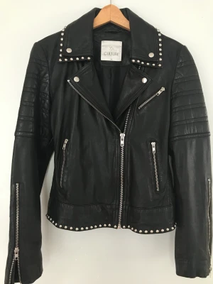 Skinnjacka  - Fräck figursydd skinnjacka i fint mjukt äkta skin med nitar. I nyskick då den använts endast vid ett tillfälle. Storlek 38.