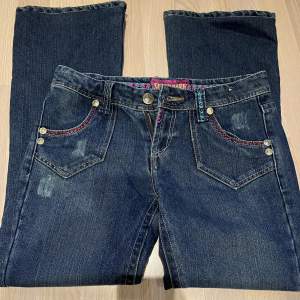 Säljer dessa lågmidjade jeans på grund av att jag köpte de av någon annan men de passade ej. De är utsvänga och har färgglada detaljer vid fickorna.  Midjemått - 40 cm  Innerbenslängden - 72 cm Jag är runt 160 och de passade på längden. 