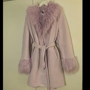 Kappa  - Oanvänd syrenlila kappa med fuskpäls på ärmslut och krage. 