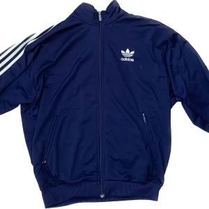 Adidas zip up - Asfet adidas zip up hoodie med en cool passform nästan som en bomberjacka! Mini fläckar av färg som säkert kan tas bort med något medel men annars är fläckarna inget man tänker på. Säljer då den inte kommer till användning längre. Skriv för mer frågor!😊