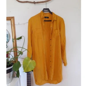 Gul Skjorta - Gul lång skjorta från Pieces i mycket bra skick. Två fickor på framsidan och bronsiga knappar. Storlek S 🌼 