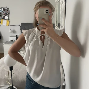 Blus - Vit knytblus med volanger på axlarna från H&M. Blusen är aldrig använd och därför i nyskick! 