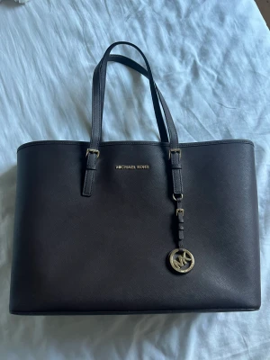 Väska - Äkta Michael Kors väska. Mörkbrun med inbyggd dator fodral. Använd ungefär 2/3 gånger. Så nyskick. Michael kors dustbag medföljer. Nypris: 3800kr  ✉️ Frakt kan tillkomma, köparen står för frakten.  📍 Kan mötas i Tyresö. 💸 Vid snabb affär kan priset diskute