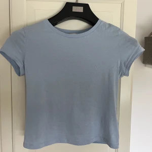 Blå basic t-shirt - Fin blå tshirt från HM. En aning croppad men går ändå över naveln på mig som är 163cm. Säljer då jag inte använder den.
