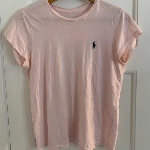 Ralph Lauren t-shirt - Säljer denna rosa Ralph Lauren t-shirten. Storleken har skavts bort men den passar en xs/s. Bra skick. Dock ett litet hål i kragen, väldigt litet.
