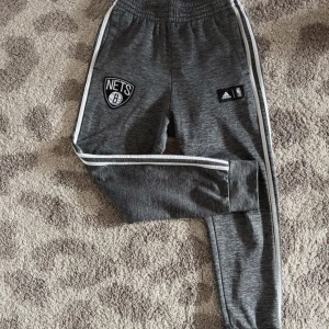 Adidasbyxor- NBA - Adidasbyxor i bra skick. Lite noppriga som vid bilden med NBA-märket. + att etiketten är helt tom (se bild). Längd 94 cm. Bredd midja 36 cm gånger två.  Går att dra åt med snöre. OBS‼️Är lite osäker på om storleken är XS eller S då etiketten saknas.   