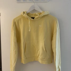 Hoodie - Ljusgul hoodie med ett litet hjärta på.