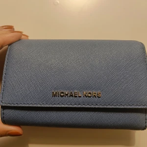 Blå Michael Kors plånbok - Aldrig använd, nyskick. Rymmer mycket med men ändå kompakt. Finns med tillhörande väska för 2200 (pris kan diskuteras!).