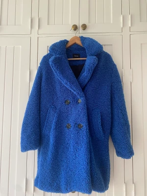 Bershka Blå Kappa  - Bershka blå kappa i bra kvalite. Varm jacka, fluffig, går att knäppa på olika sätt