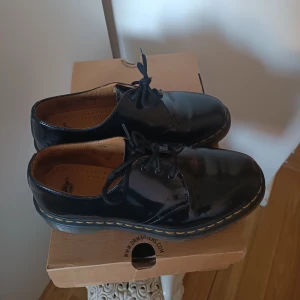 Låga Dr Martens 1461 - Låga Dr Martens i storlek 41. Modell 1461 (3 eye shoe patent lamper). I skinn med lackerad yta. I fint skick, använda ett fåtal gånger. Nypris 1800 kr. 