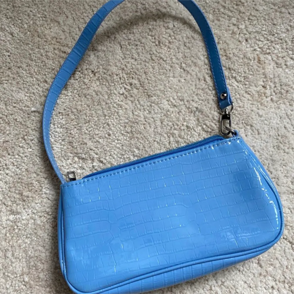 En liten blå handväska med syntet skinn, hör av er vid frågor . Väskor.
