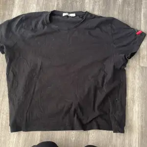 En svart t-shirt med ett körsbärsmotiv på vänster axeln.