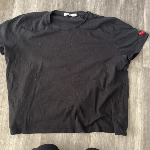 T-shirt  - En svart t-shirt med ett körsbärsmotiv på vänster axeln.