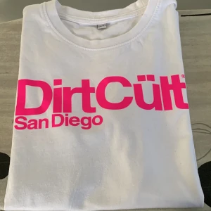 Dirtcult t-shirt  - Hej nu säljer jag min Dirtcult t-shirt då den bara ligger i garderoben. Den är vit med rosa tryck. Storleken är 158/164, den är i bra skick då den knappt är använd. 