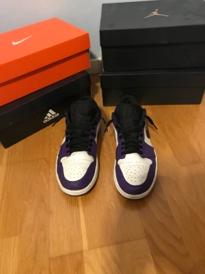 Jordan 1 Low Court Purple - Ett par schyssta Air Jordan 1 Low Court purple. Väl omändertagba men säljs pga. sällan använda och då jag tänkt använda pengarna till ett par Air Force 1. Svagt creasade,  dm för tydligare bild. Priset är förhandlingsbart. 