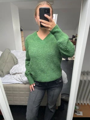 Grön stickad tröja - Grön stickad tröja med v-ringning från Arket. Använd endast 1 gång och i nyskick. Materialet är alpacka och ull. Köparen står för frakten.