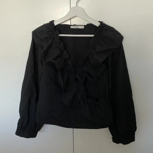 Svart blus - Jättefin svart blus med volanger. Endast använd 1 gång (nyskick)