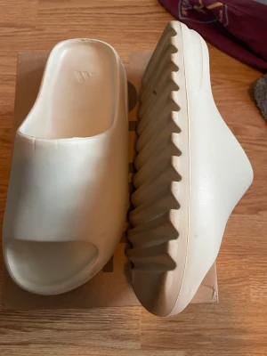 Adidas Yeezy slides bone  - Nästan helt nya yeezy slides. Använt i 2 dagar och dem blev lite stora efter som jag blev tillsagd att köpa en storlek större.. Utgångs pris 1500 men kan sänka priset om snabb affär 