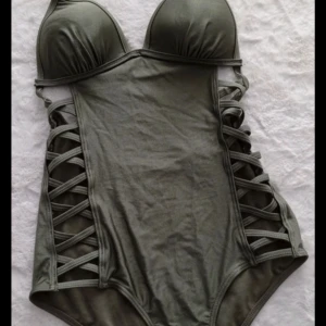 Fin och unik baddräkt i grönt! - Supersnygg och väldigt unik baddräkt i grönt/oliv med öppen rygg. Passar storlek S-M med A-B kupa och aldrig använd, helt ny! ❤️