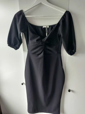 Svart klänning - En svart klänning med knut vid bysten.  Figursydd klänning från Nelly i storlek S. Aldrig använd. 