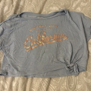 En blå tröja  -  En blå tröja med rosa glittrig text 