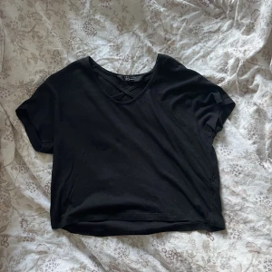 Svart t-shirts - Säljer en svart T-shirt i en kortare modell med detalj längst fram. Storlek 152/158 men sitter bra på mig som har S/M💕