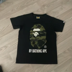 Bape t-shirt - Bape t-shirt, storlek s men funkar som Xs, det står ladies men fungerar för både tjejer och killar. Har lite slit på trycket och lite slapp i kragen men inget som man tänker på när den sitter på. 