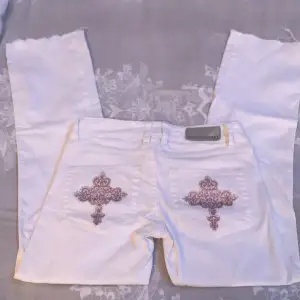 Super fina  vita lågmidjade jeans med rosa kors på bakfickorna, storlek xs men passar 34 och neråt 