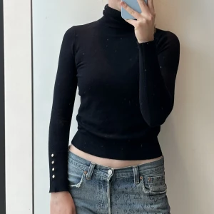 Zara topp svart - Zara topp i svart. Jättebra skick, dom vita fläckarna i första bilder kommer från spegeln. Ärmarna har guldiga nitar. Tröjan sitter tajt med har är stretchig. 